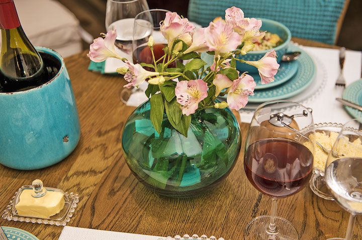Não é porque você vai comer em casa que a mesa não precisa de capricho. Um bom vinho para acompanhar e flores no vaso de vidro azul fazem toda a diferença.