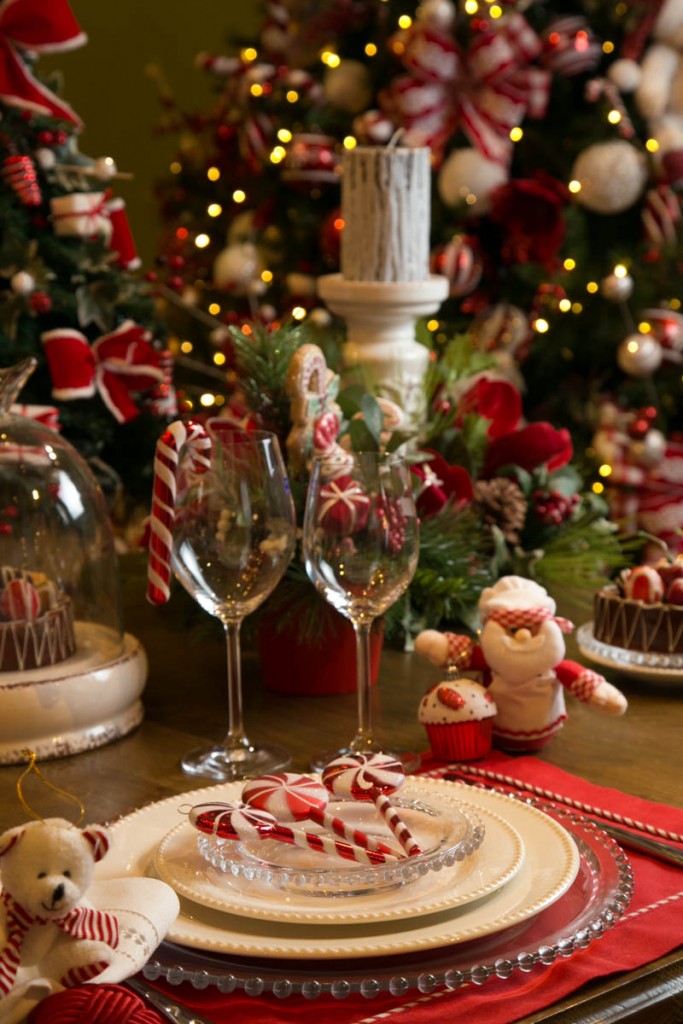 Outro mimo para os convidados, o Papai Noel, de avental, traz um cupcake gigante recém confeitado. E uma bengalinha enfeita o copo de vinho. Todos são enfeites de árvore que vieram para a mesa.