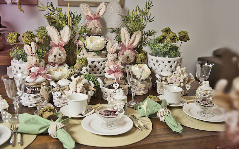 Em tons pastéis, a mesa cheia de coelhas com flores e laços cor de rosa, cria uma atmosfera de sonho.