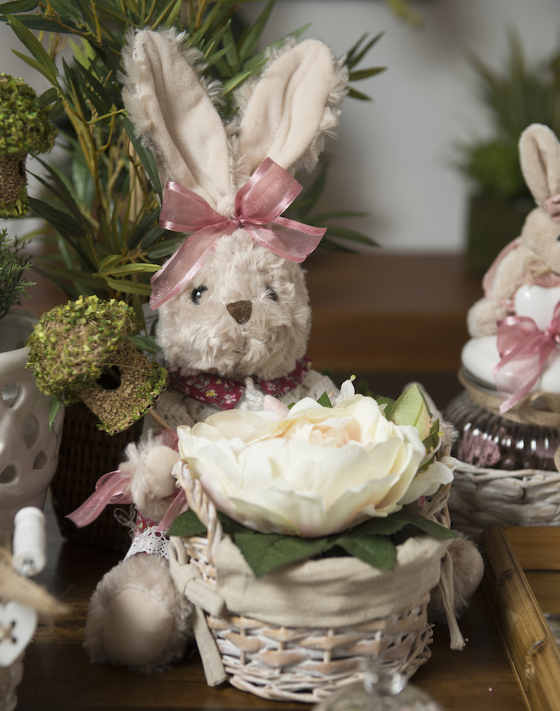 A coelha com cesta de vime serve de cachepot para um mini arranjo de rosas e uma casa de passarinho. Mas também poderi estar carregando ovos de Páscoa. 