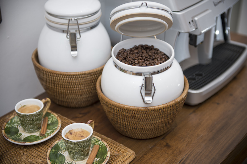 Ao lado da máquina de expresso em grãos, o pote hermético conserva o aroma e o frecor do café com muito charme.