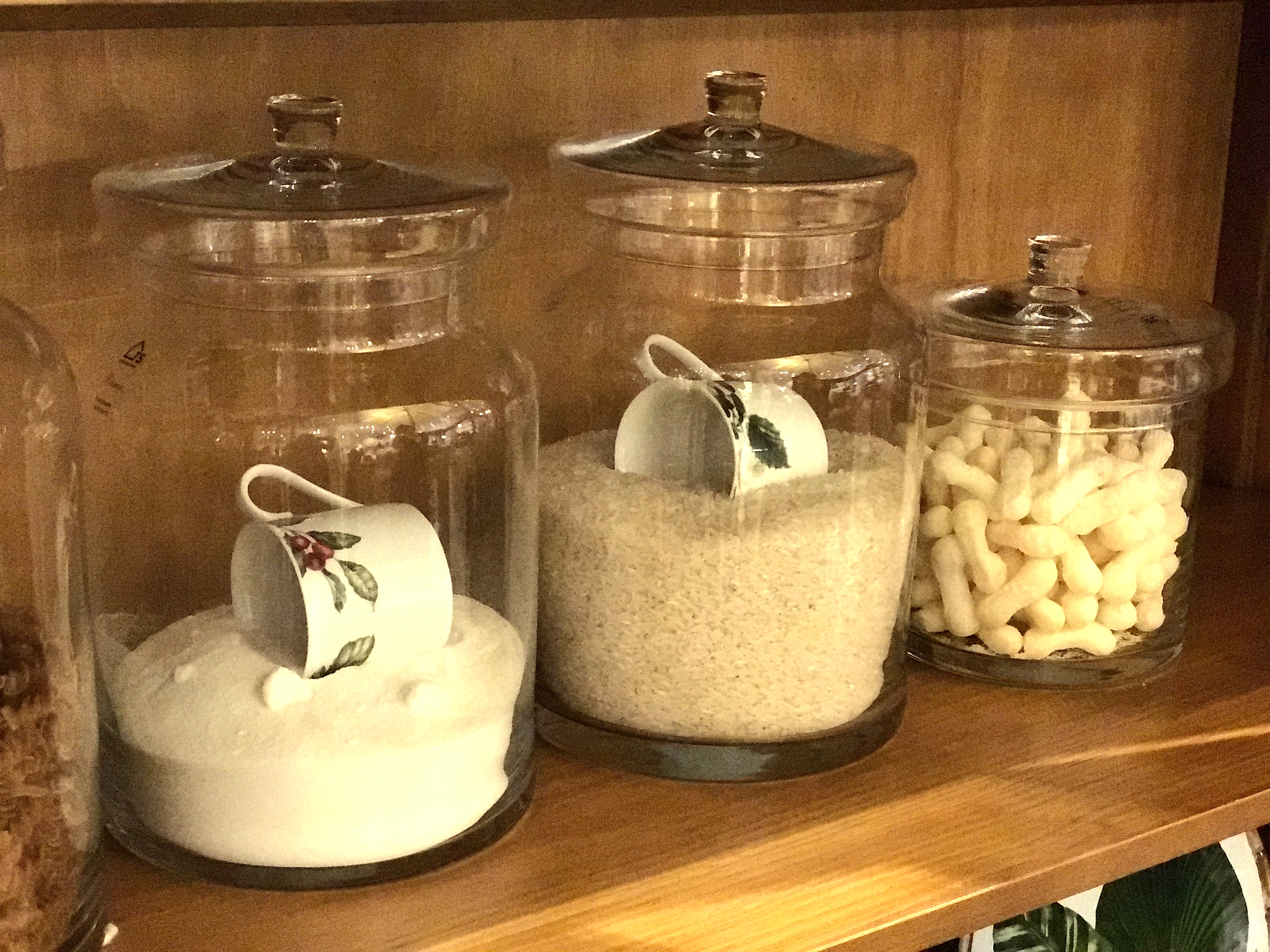 Os vidros com tampa servem ao mesmo tempo de decoração e porta-mantimentos. O toque de charme fica por conta das xícaras de porcelana, usadas como medida.