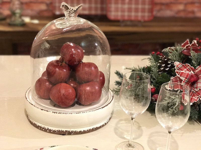 Prato com tampa de vidro recheado de maçãs vermelhas para centro de mesa.