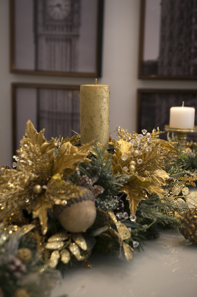 O centro de mesa une poisentias (a flor do Natal) douradas, misturadas a ramos de cristal, além de pinhas e nozes.