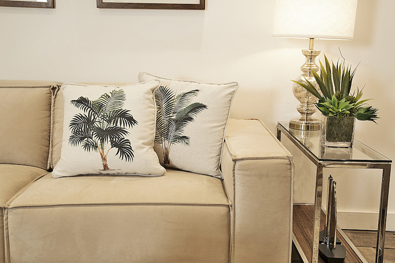 Almofadas de coqueiros, por exemplo, trazem o estilo Jungle para a sala sem precisar de muitos vasos.